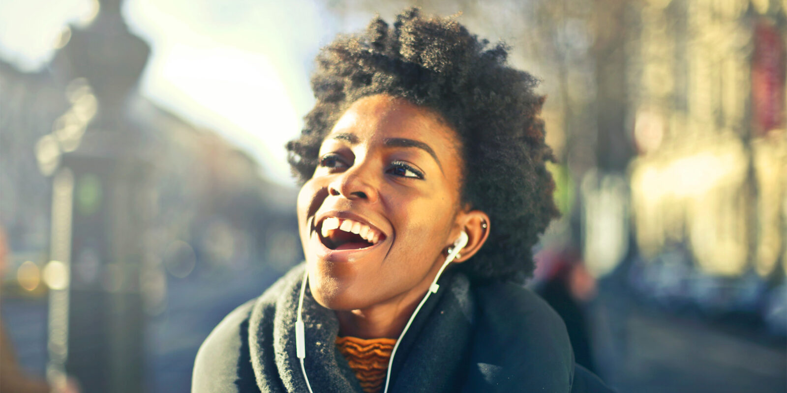black woman smiling listening with earbud headphones