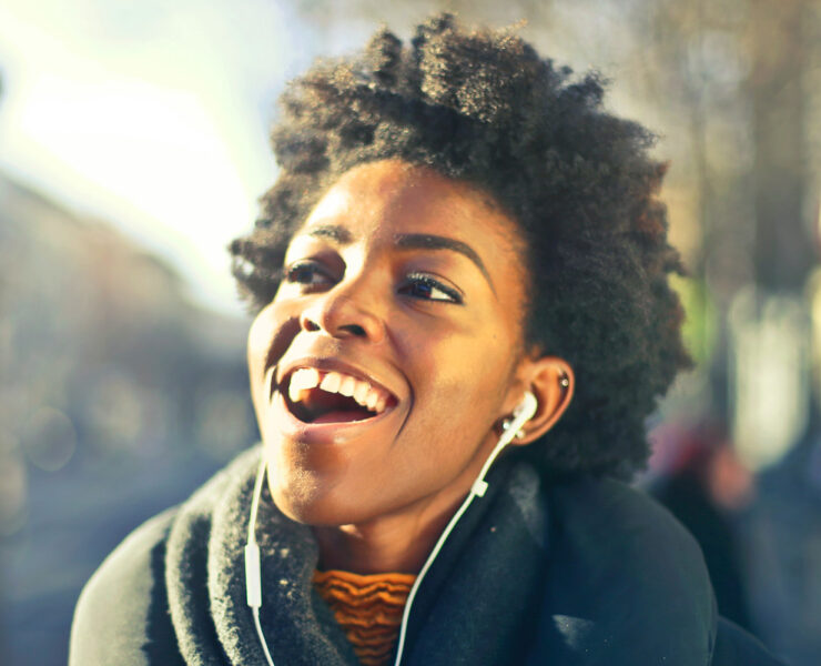 black woman smiling listening with earbud headphones